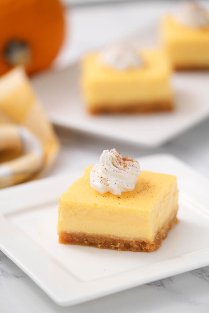 Creamy Pumpkin Cheesecake Bars that taste just like pumpkin pie but in cheesecake form! Perfect alternative to pie for this holiday season! cheesecake topped with whipped cream.
