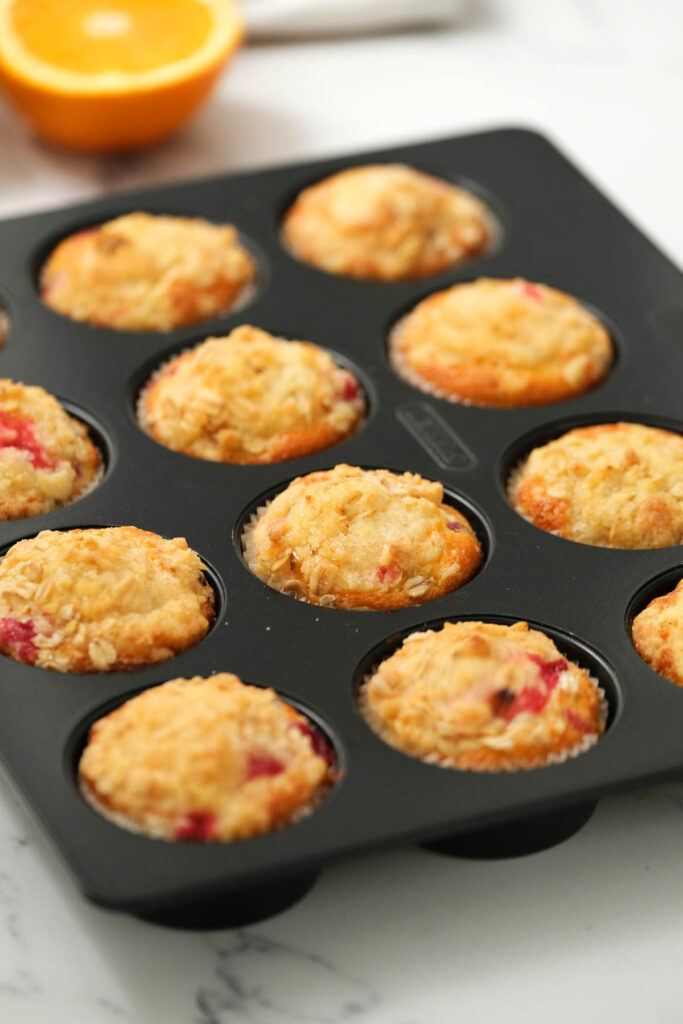 These Cranberry Orange Muffins are moist and flavorful! topped with a buttery crumb topping! Just like a bakery! cranberry orange muffins in muffin pan.