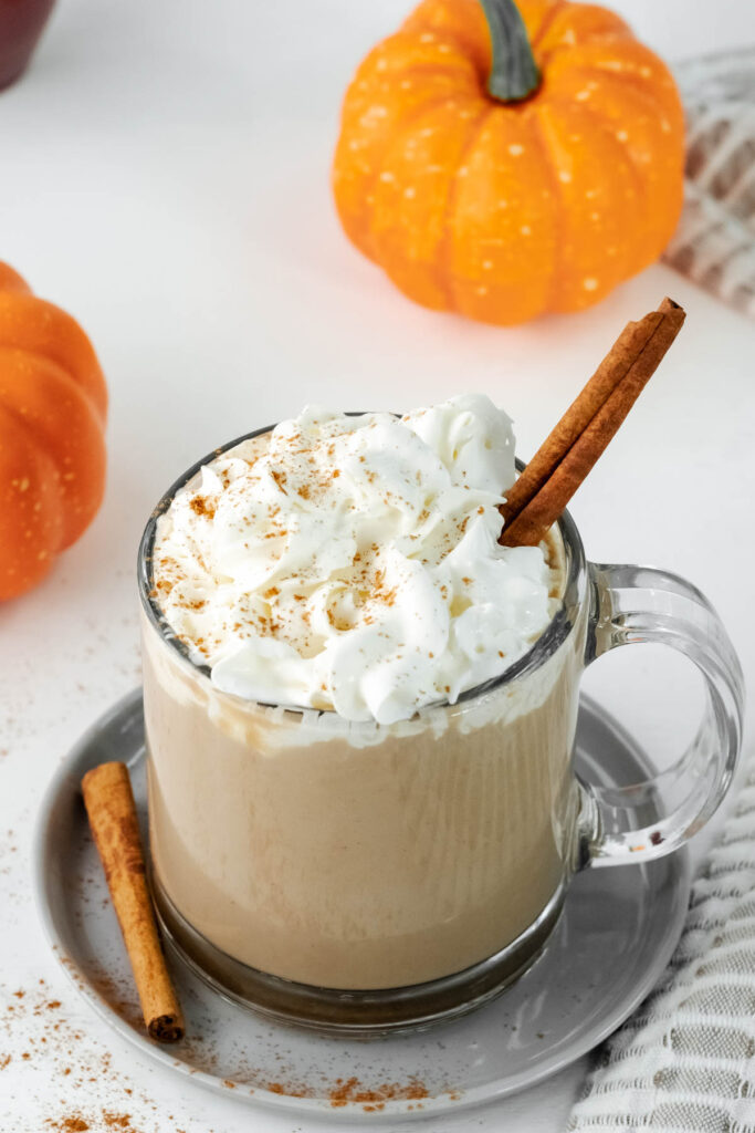 This Pumpkin Spice Latte taste just like the big chains! You can easily make it at home for the same great taste! latte in glass cup with cream topped with cinnamon.