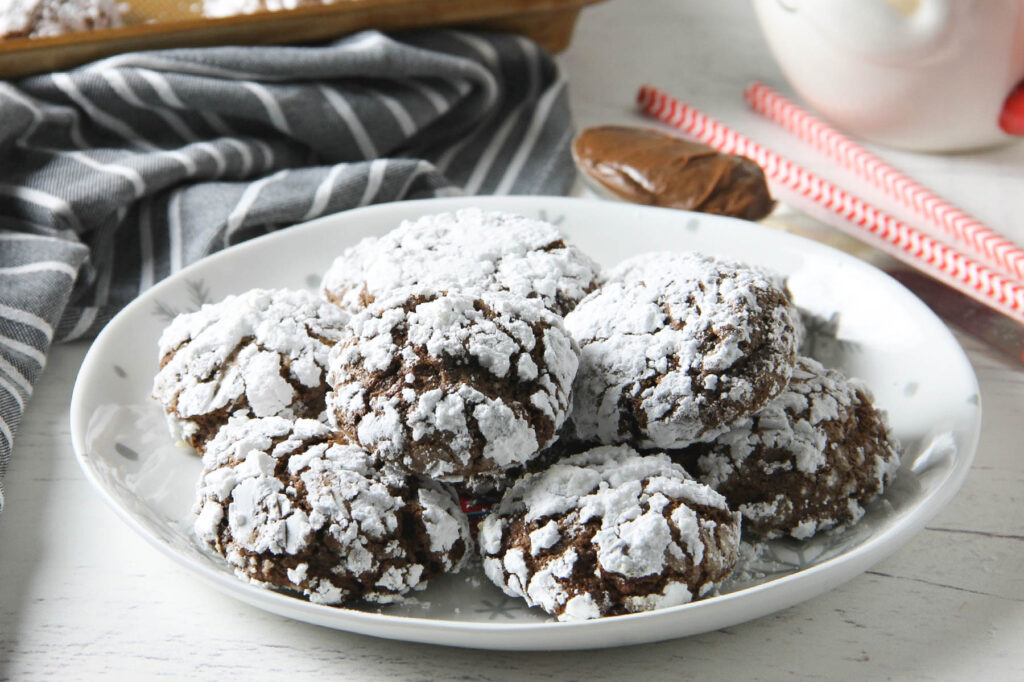 Chocolate Hazelnut Crinkle Cookies are impossible to resist. They're made with the sweet addition of creamy hazelnut spread! Chocolate Hazelnut Crinkle Cookies stacked on plate.