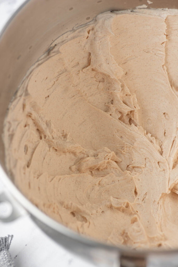 A fast, simple Cinnamon Buttercream Frosting! Light and fluffy frosting that goes well on cake, cupcakes, and cookies! Cinnamon Buttercream Frosting mixed in metal mixing bowl.