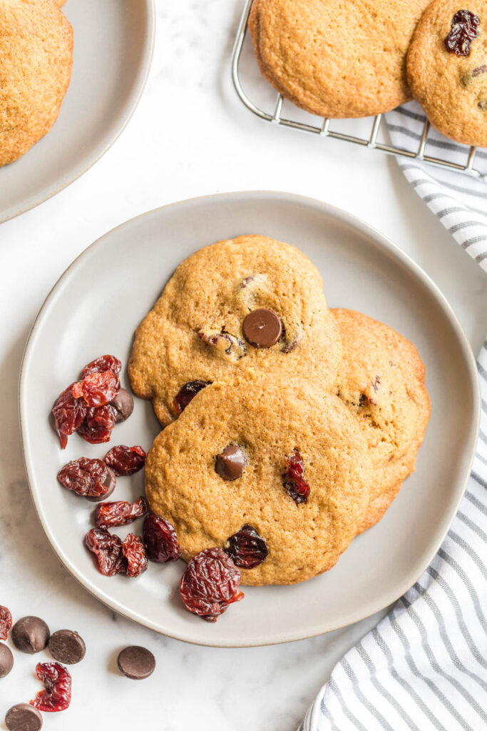 Soft, buttery Dark Chocolate Chip Cherry Cookies! Flavored with a touch of almond extract and lots of dark chocolate! Dark Chocolate Chip Cherry Cookies on plate with dried cherries.