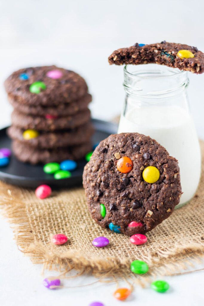 These Double Chocolate Monster Cookies have lots of texture with a little bit of crunch. Double Chocolate Monster Cookies in front of a glass of milk.