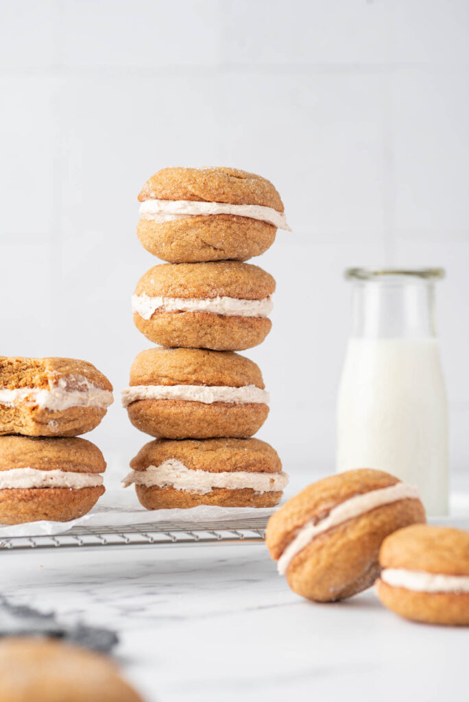 Soft and fluffy Ginger Molasses Cookie Sandwiches! Filled with a cinnamon buttercream frosting! Perfect for any cookie tray! Ginger Molasses Cookie Sandwiches stacked on top of each other.