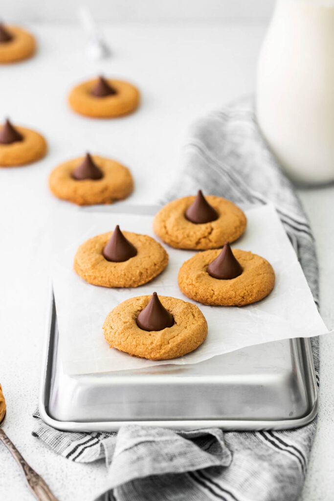 Soft and chewy Peanut Butter Blossom Cookies! A classic cookie filled with creamy peanut butter and chocolate kisses! cookies with chocolate kisses on parchment paper.