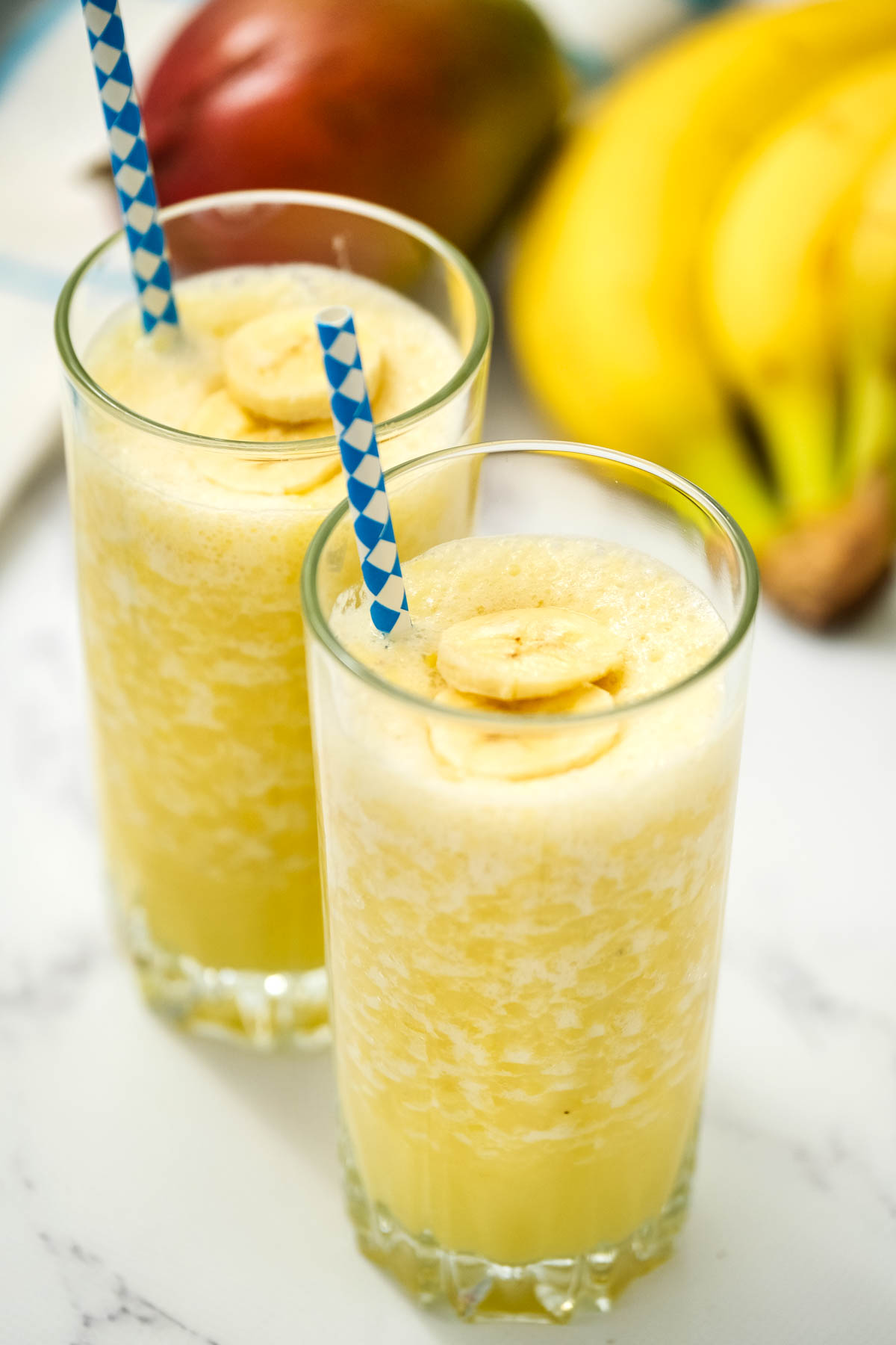 Mango Banana Smoothie in glassed with fresh fruit.