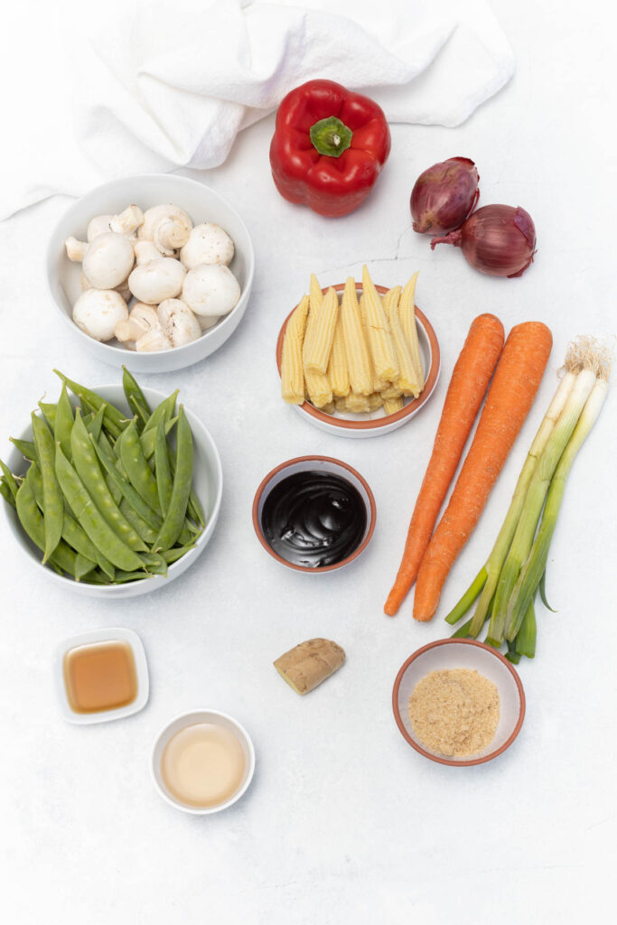 Easy Instant Pot Vegetable Stir Fry filled with hearty vegetables, covered in a sweet and savory sauce. stir fry ingredients on white background.