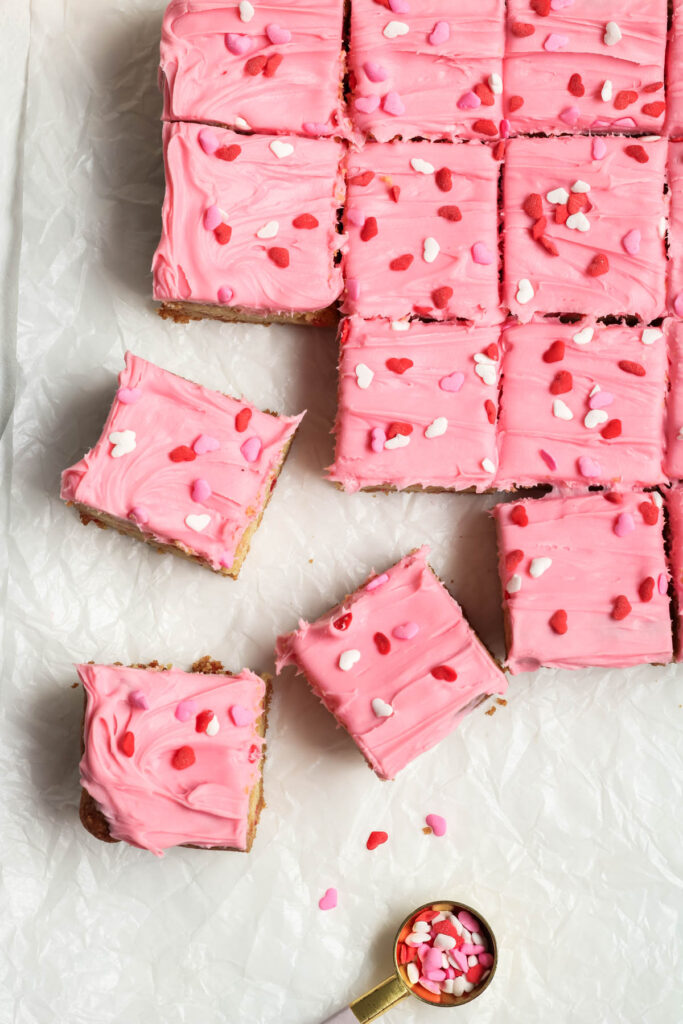 Easy Strawberry Frosted Cookie Bars made with 3 ingredients! Perfect for an easy treat that even the kids can make! Strawberry Frosted Cookie Bars on parchment paper with sprinkles.
