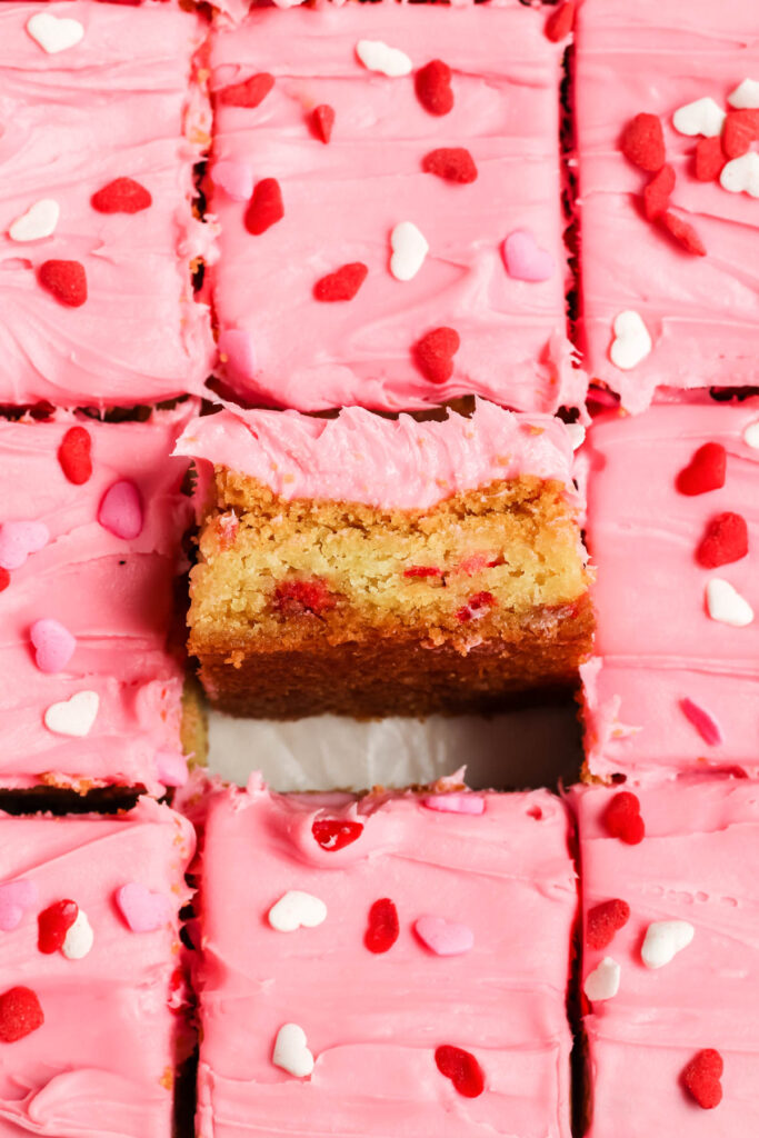 Easy Strawberry Frosted Cookie Bars made with 3 ingredients! Perfect for an easy treat that even the kids can make! Strawberry Frosted Cookie Bars with square pulled up in center.
