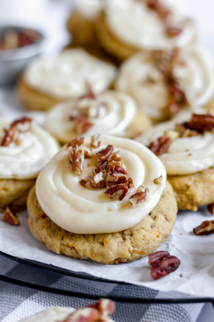 These carrot cake cookies are delicate and light! Topped with a fluffy creamy cheese frosting! Taste just like cake but easier to make! close up of cookie with frosting and pecans.