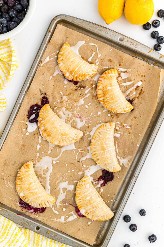 These Lemon Blueberry Turnovers are a quick and easy hand pie! Filled with lemon curd and fresh blueberries! Perfect hand held dessert! Lemon Blueberry Turnovers on sheet pan.