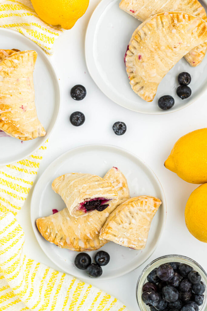 These Lemon Blueberry Turnovers are a quick and easy hand pie! Filled with lemon curd and fresh blueberries! Perfect hand held dessert! Lemon Blueberry Turnovers on white plates.