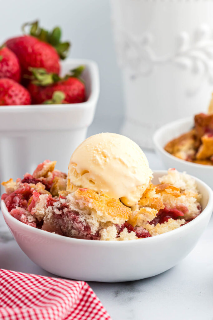 Easy Strawberry Cobbler! With an easy buttery crust mixed with fresh strawberries, this 6 ingredient dessert is perfect for summer! Strawberry Cobbler in white bowl.