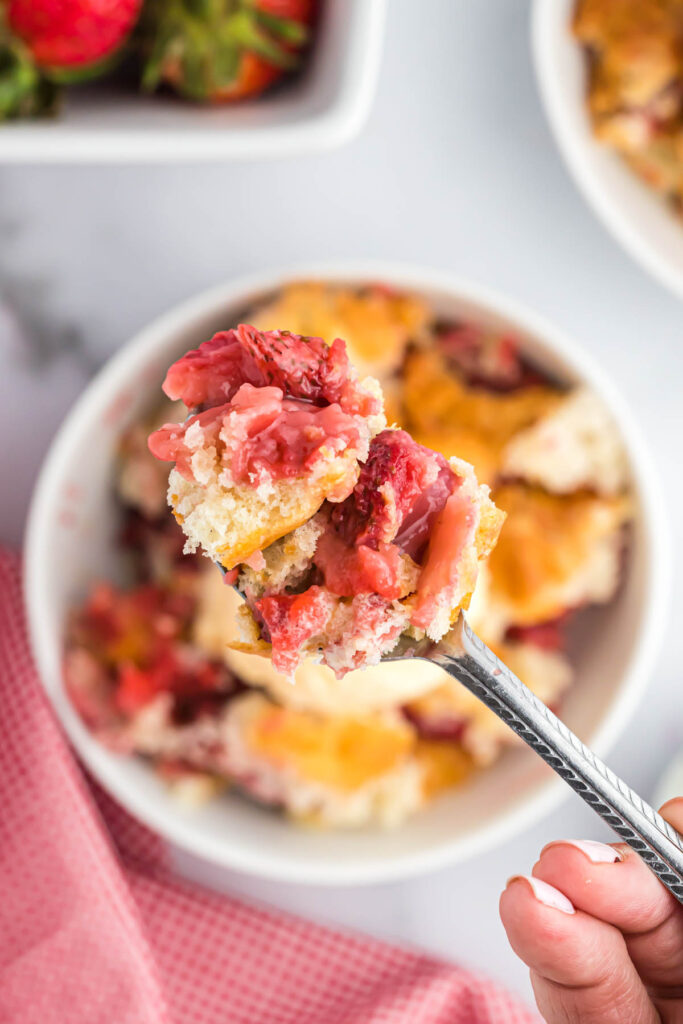 Easy Strawberry Cobbler! With an easy buttery crust mixed with fresh strawberries, this 6 ingredient dessert is perfect for summer! Strawberry Cobbler in spoon.