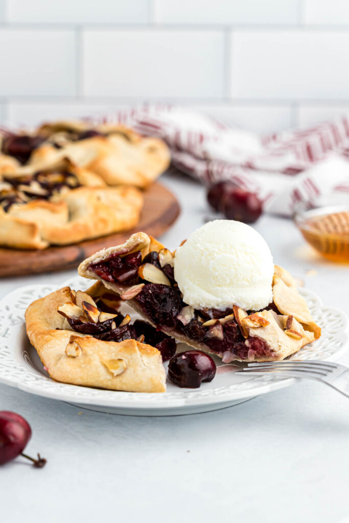 Mini Cherry Almond Galettes are the perfect individual desserts! Filled with fresh cherries, honey and almonds. Baked to perfection! Mini Cherry Almond Galettes on white plate with ice cream.