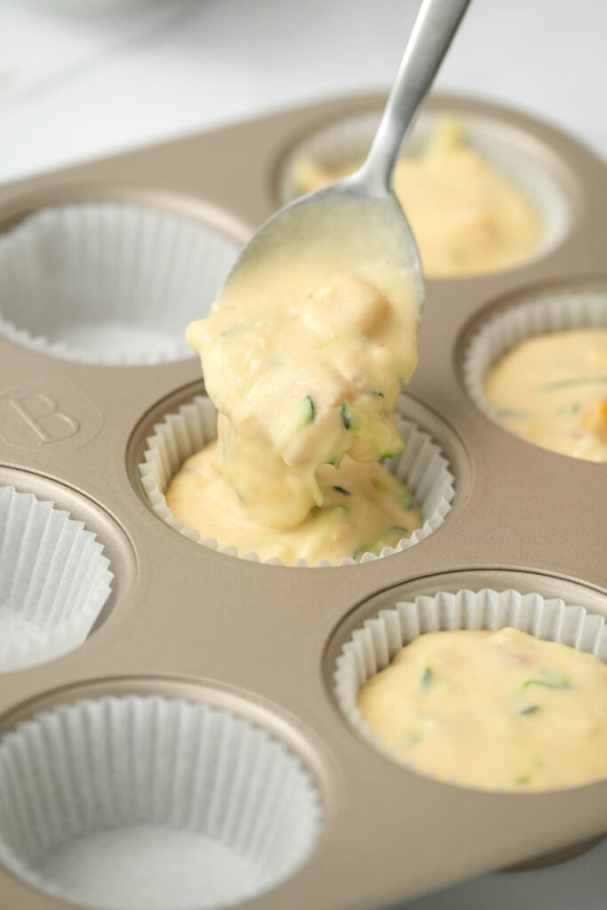 pouring muffin mix into liners.