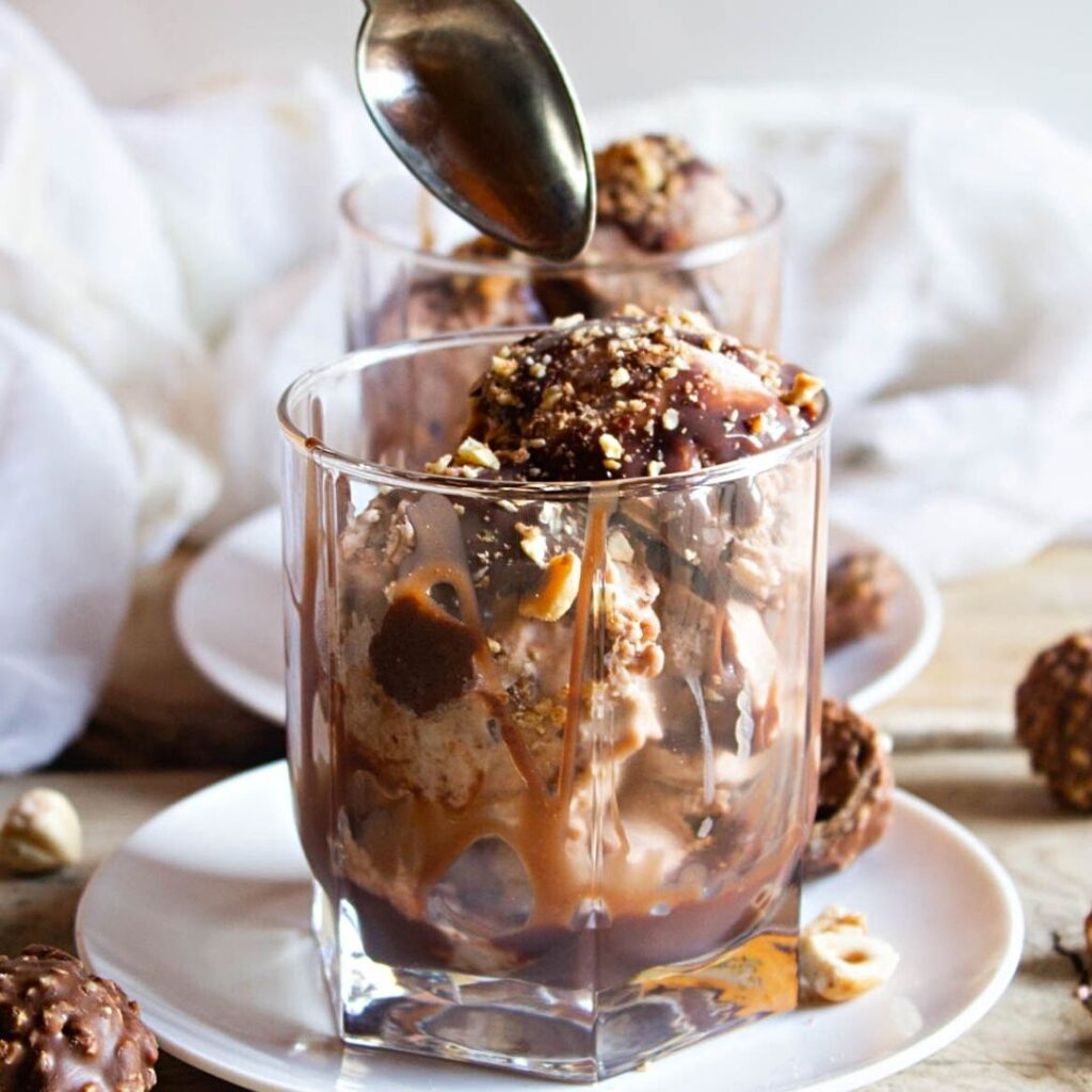 No churn Ferrero Rocher Ice Cream! A delicious creamy hazelnut chocolate ice cream that is the ultimate summer treat! dipping spoon into ice cream.
