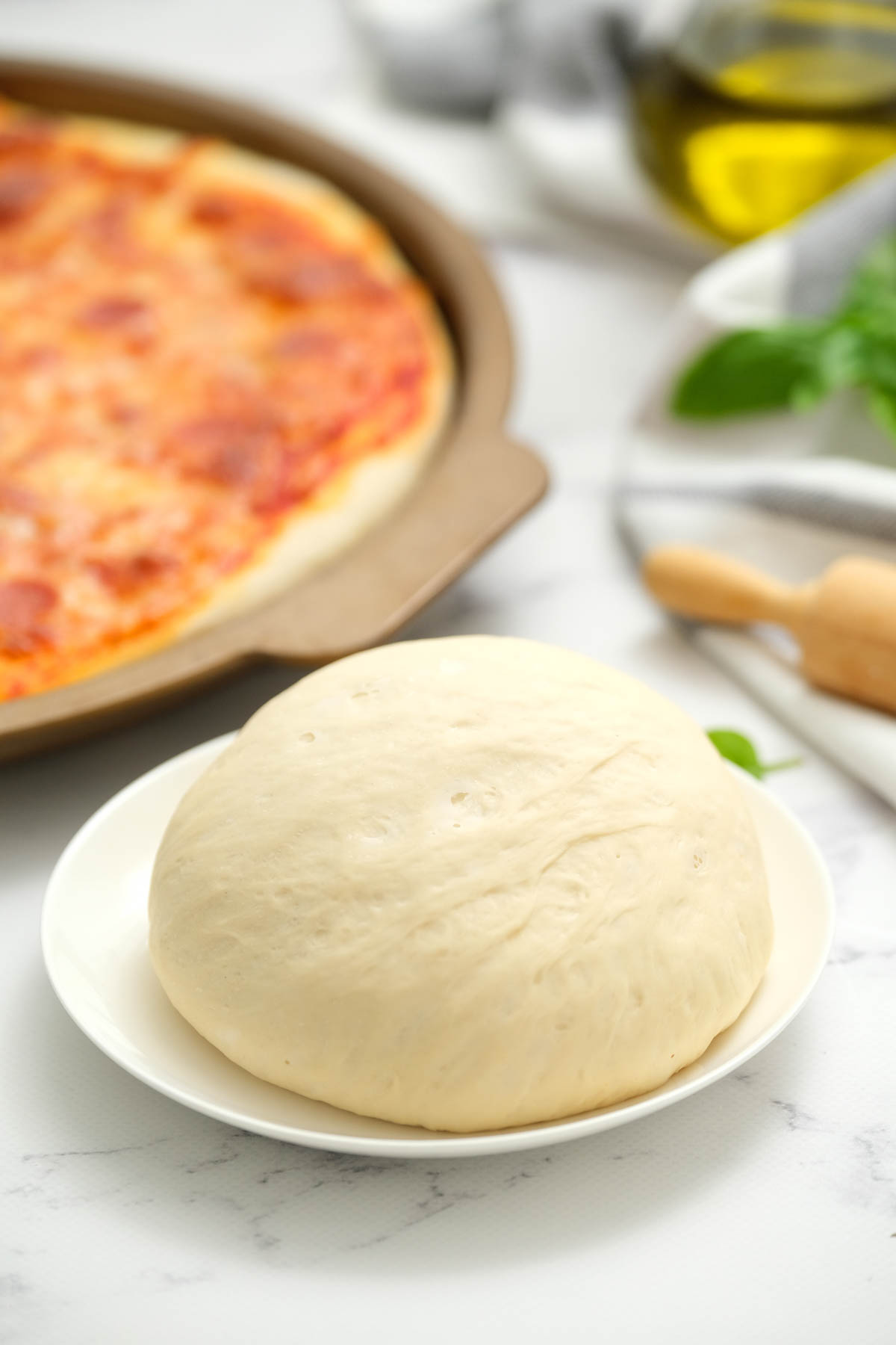 This homemade Pizza Dough recipe is perfect for any pizza night! Comes together in just a few minutes with just a few ingredients! uncooked Pizza Dough on white plate.