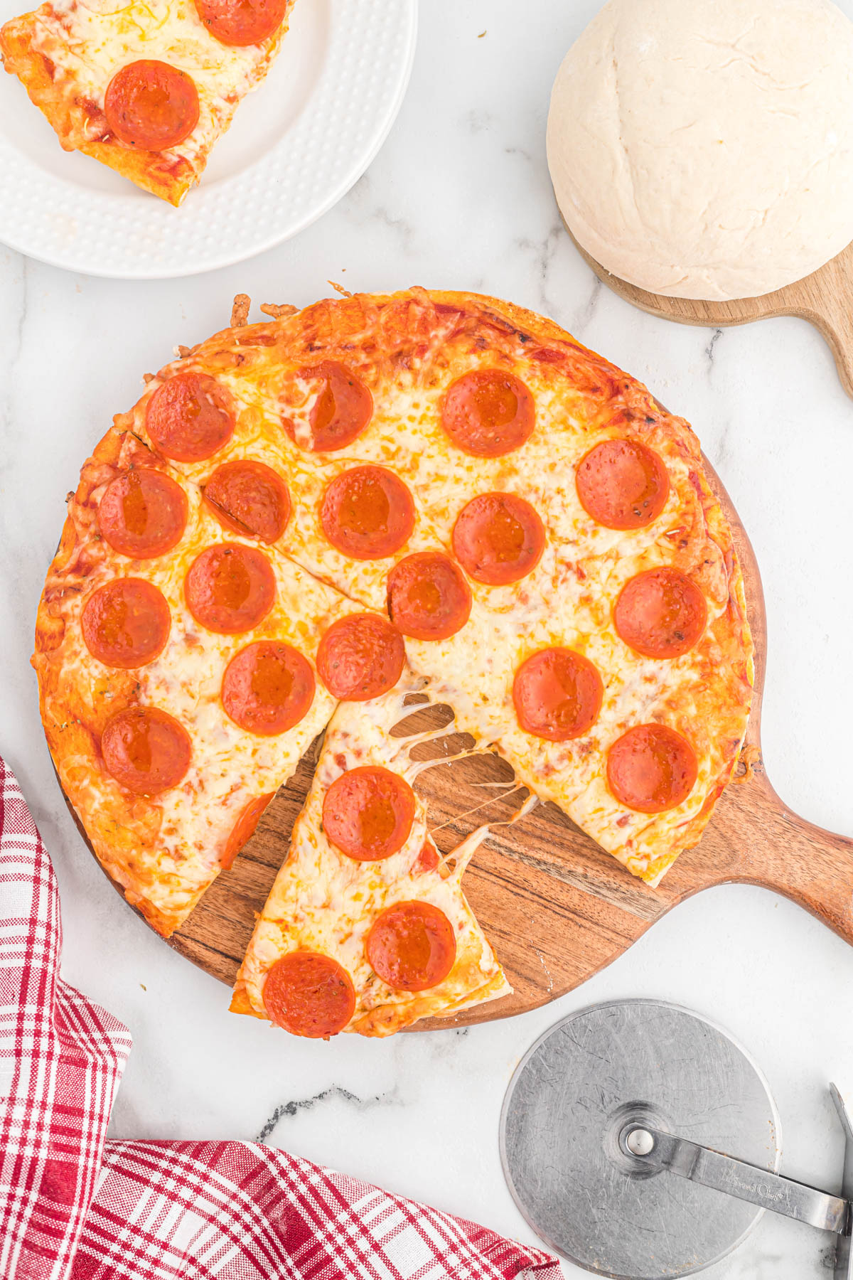 This homemade Pizza Dough recipe is perfect for any pizza night! Comes together in just a few minutes with just a few ingredients! cooked pizza on cutting board.
