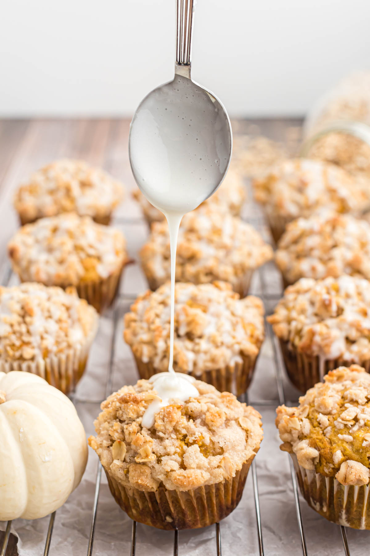Fall inspired muffins that are perfect for a busy morning! These Pumpkin Oatmeal Muffins will not disappoint! They are so delicious! drizzling glaze over muffins.