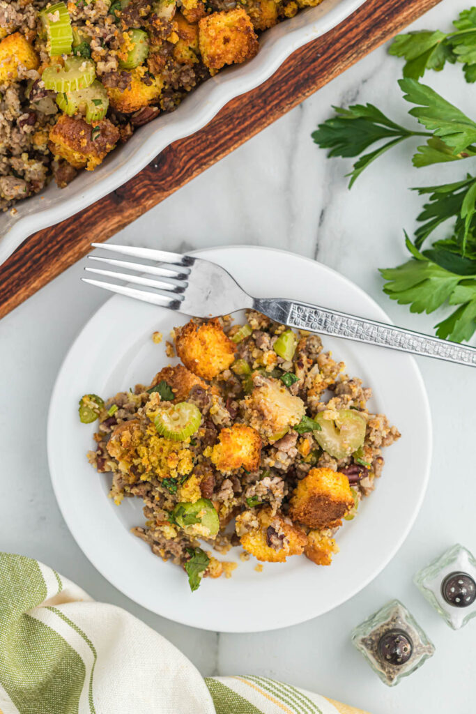 Savory sausage cornbread stuffing, with lots of flavor, seasonings and versatile for any meal with a little added crunch of pecans! cornbread stuffing on white plate with sausage.