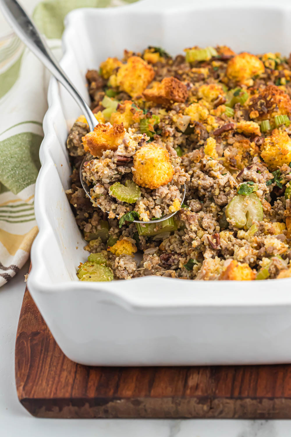 Savory sausage cornbread stuffing, with lots of flavor, seasonings and versatile for any meal with a little added crunch of pecans! sausage cornbread stuffing in white serving dish.