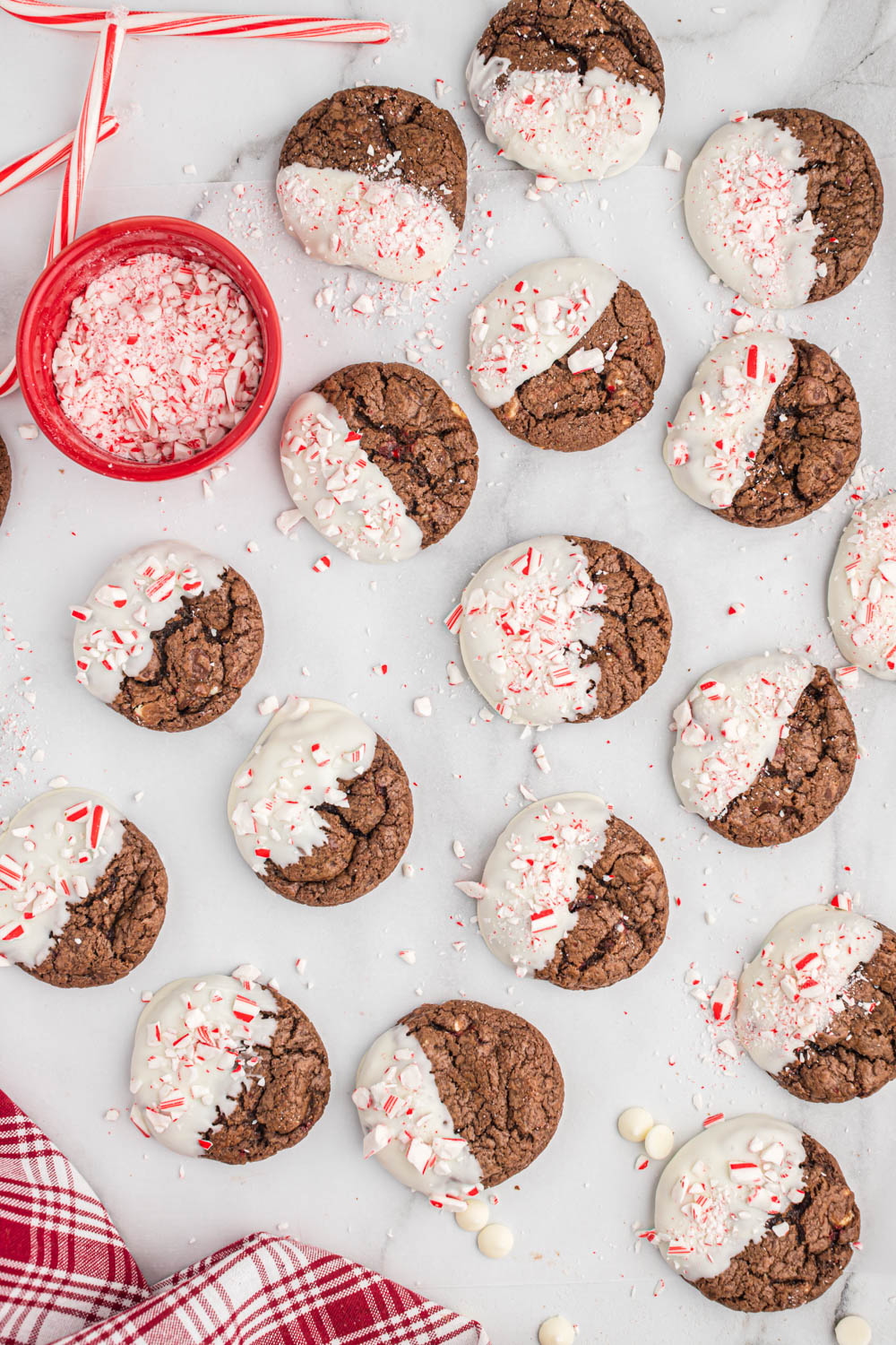 Easy chocolate peppermint bark cookies that are ready in no time! Full of peppermint flavor, these soft and gooey cookies are perfect! cookies laid out on white background with candy canes.