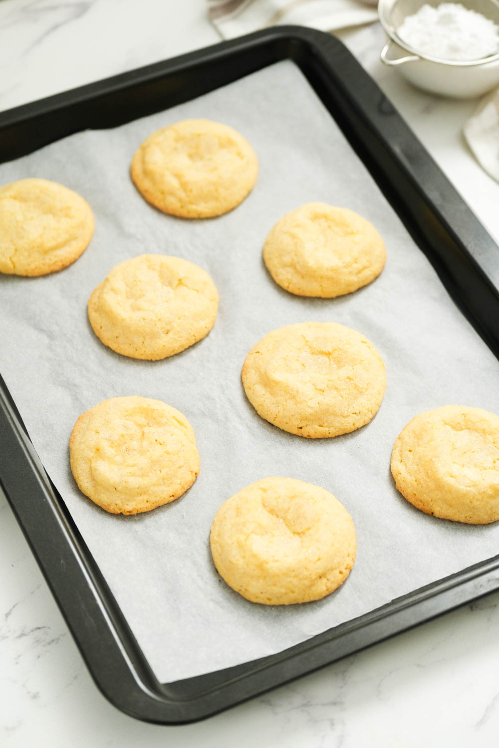 These frosted eggnog cookies are the perfect treat for eggnog lovers! With a touch of nutmeg and topped with eggnog buttercream frosting! cooked cookies on sheet pan.