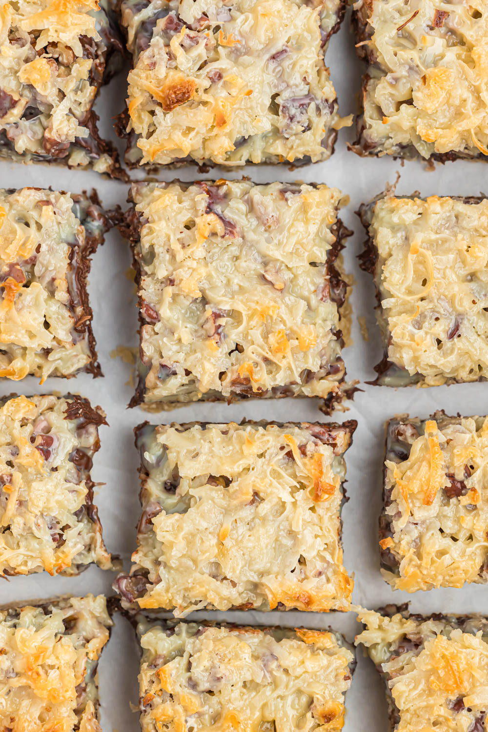 These seven layer magic bars are a classic dessert cookie bars. Made with just a few ingredients and baked to perfection! With a twist! slices of Seven Layer Magic Bars on white background.