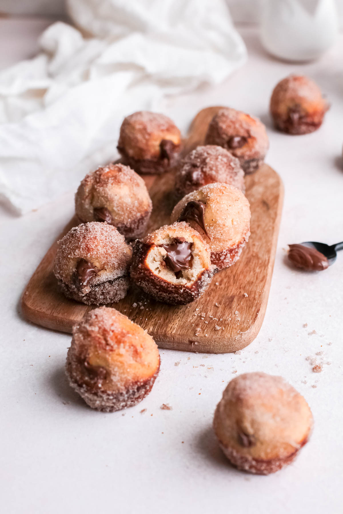 Indulge in a bite of heaven with our delicious Nutella donut holes recipe. These baked treats are easy to make and perfect for any day. Nutella Donut Holes stacked on wooden board.