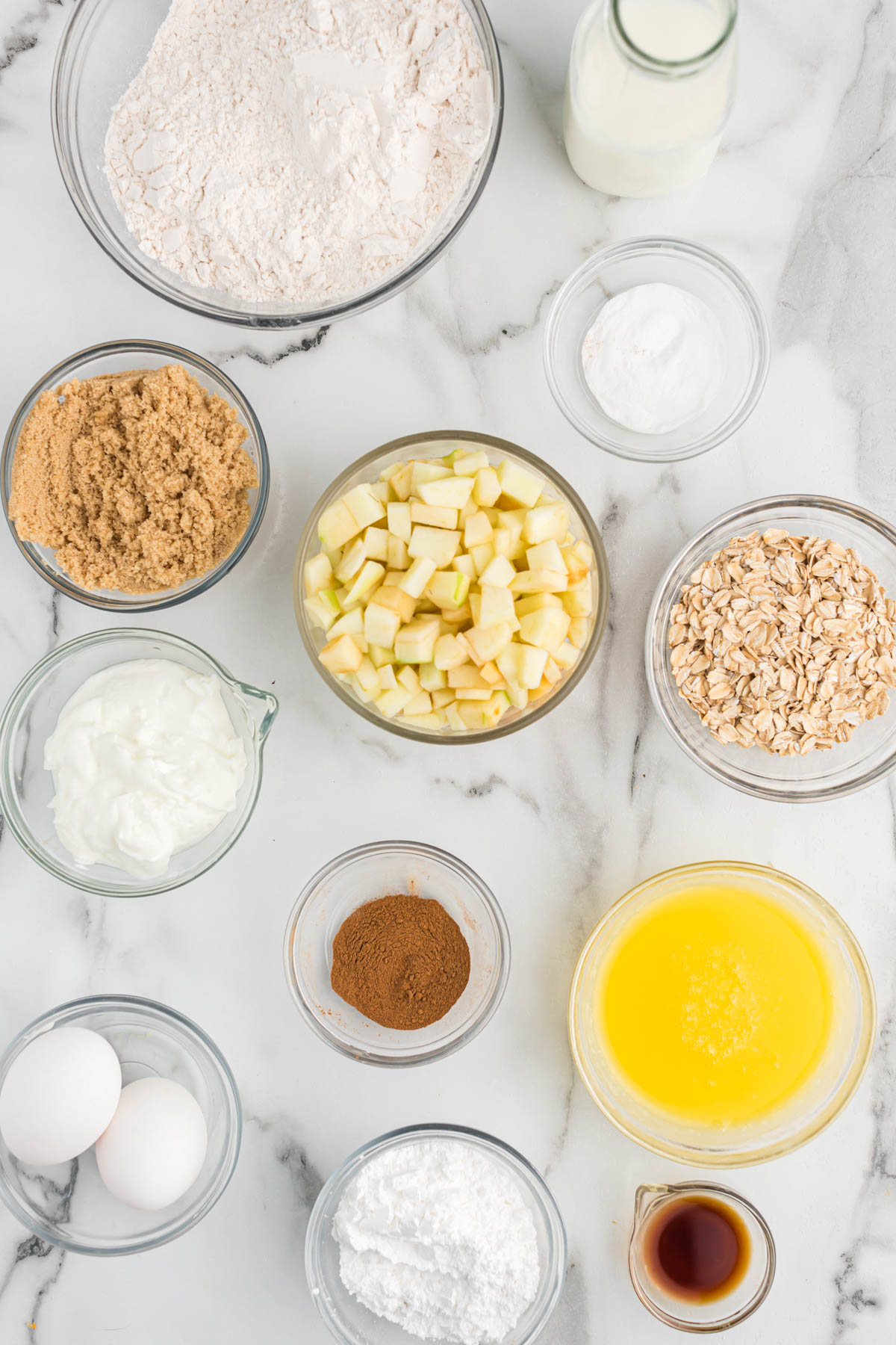 A delicious way to start the day is with these Apple Cinnamon Oatmeal Muffins. They are moist, slightly sweet and full of flavor! ingredients for apple cinnamon oatmeal muffins in glass bowls.