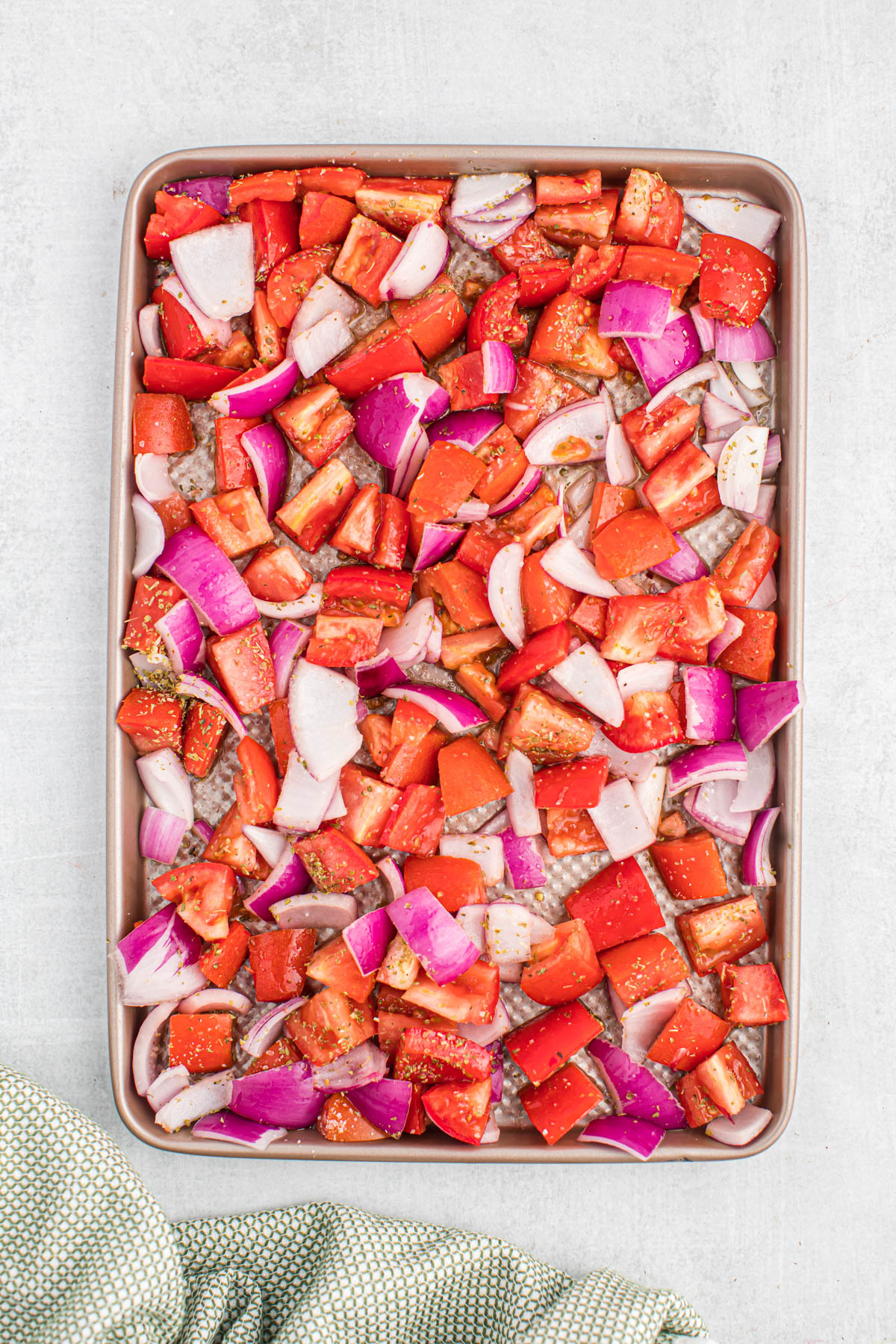 Easy to make Sheet Pan Roasted Tomatoes! Made with few simple ingredients, these tomatoes roast up in just 15 minutes! So tender and so flavorful! uncooked tomatoes and onions on sheet pan