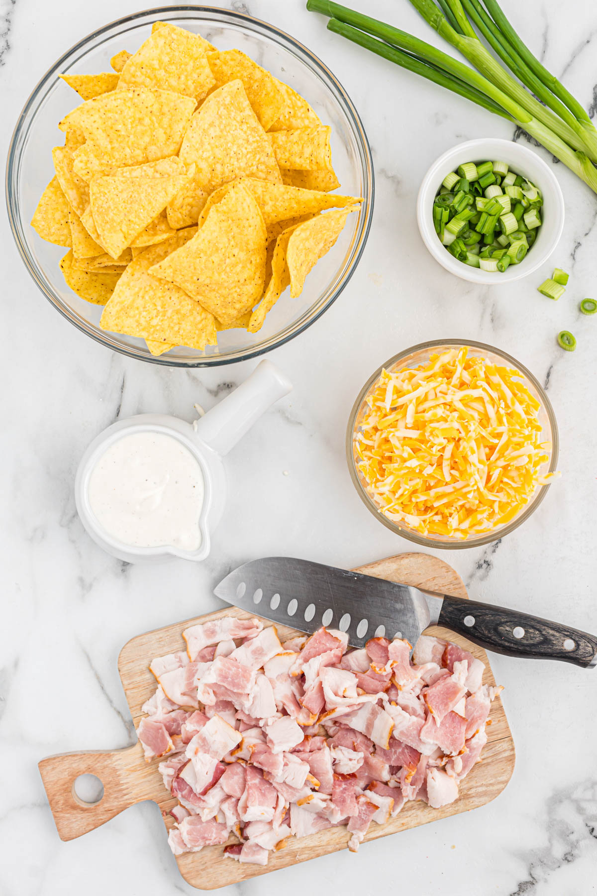 Whip up this quick and easy Bacon Ranch Skillet Nachos recipe in minutes. Crispy tortilla chips smothered in melty cheese, savory bacon, and creamy ranch dressing. ingredients for bacon ranch skillet nachos