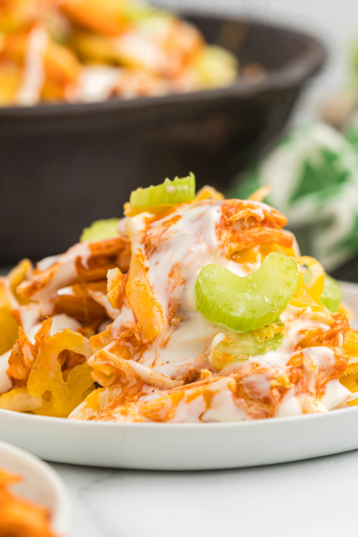 Easy to make Buffalo Chicken Skillet Nachos. Made with rotisserie chicken and buffalo sauce, this will become your new game day appetizer! nachos topped with ranch and celery