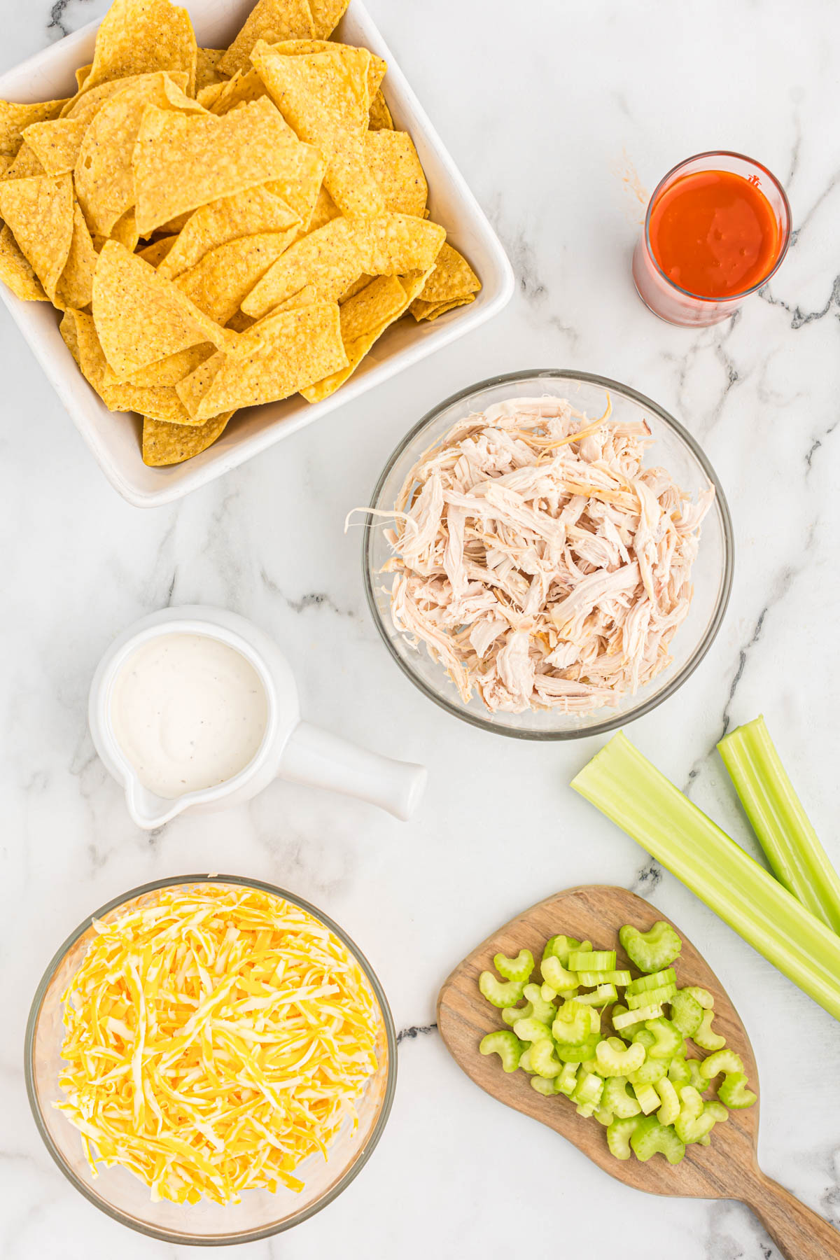 Easy to make Buffalo Chicken Skillet Nachos. Made with rotisserie chicken and buffalo sauce, this will become your new game day appetizer! ingredients for buffalo chicken skillet nachos in bowls
