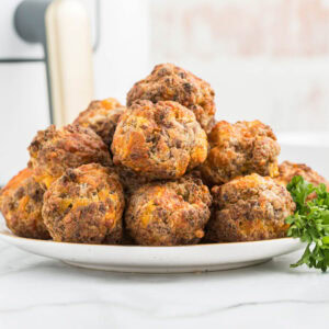 Air fryer sausage balls on white plate.
