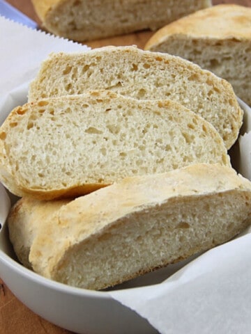 Homemade Italian Bread in gray bowl on brown cutting board