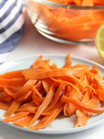 Lemon Carrot Salad on white plate with lemon