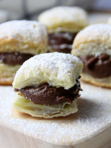 Miguelitos with Chocolate on cutting board topped with powdered sugar