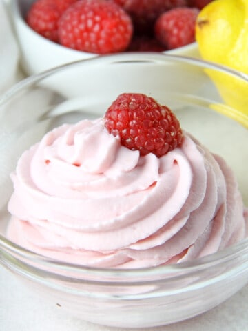 Lemon Raspberry Whipped Cream in glass bowl topped with fresh raspberry
