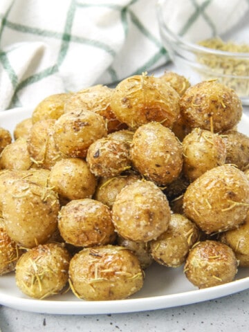 Roasted Rosemary Potatoes on white plate with spoon