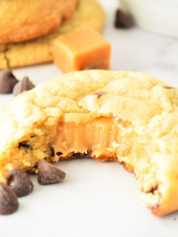 Chocolate Chip Caramel Cookies with bite and caramel oozing out