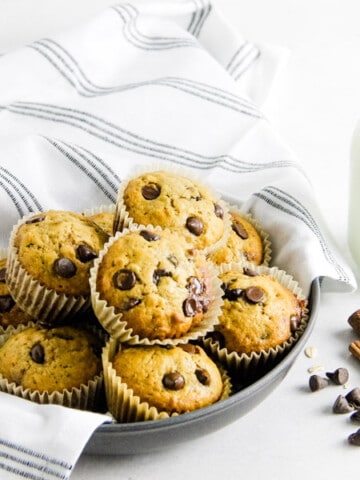 Muffins in bowl with glass of milk.