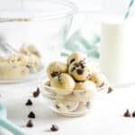 cookie dough bites in bowl with glass of milk.