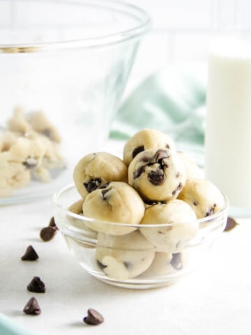 cookie dough bites in bowl with glass of milk.