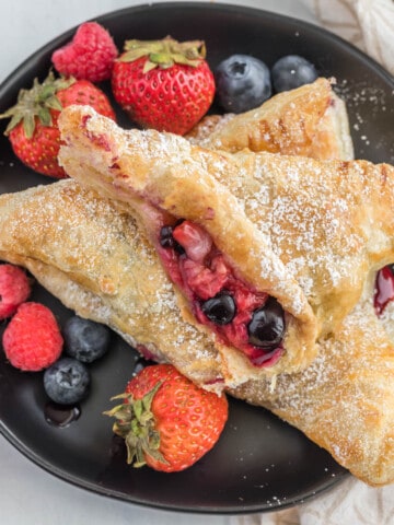 mixed berry turnover cut in half on plate.