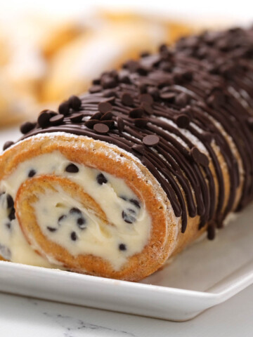 Chocolate Chip Pumpkin Roll on white plate drizzled with chocolate.