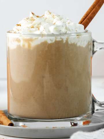 latte in glass cup topped with cream.