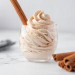 Cinnamon Buttercream Frosting piped into a glass with cinnamon stick.