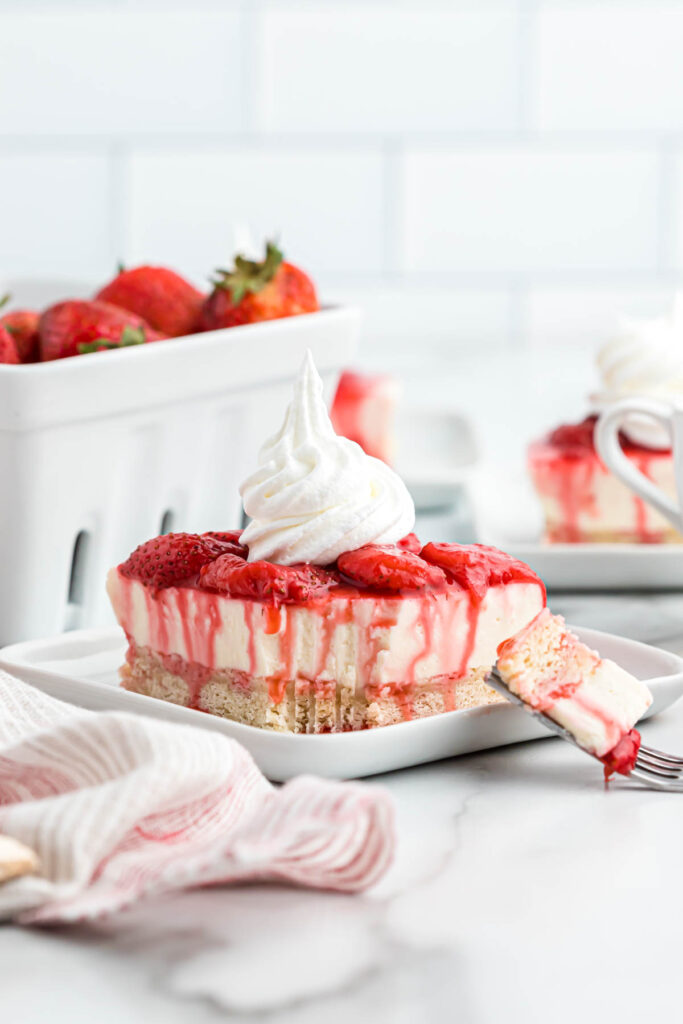 Strawberry Cheesecake Shortbread Bars topped with whipped cream.